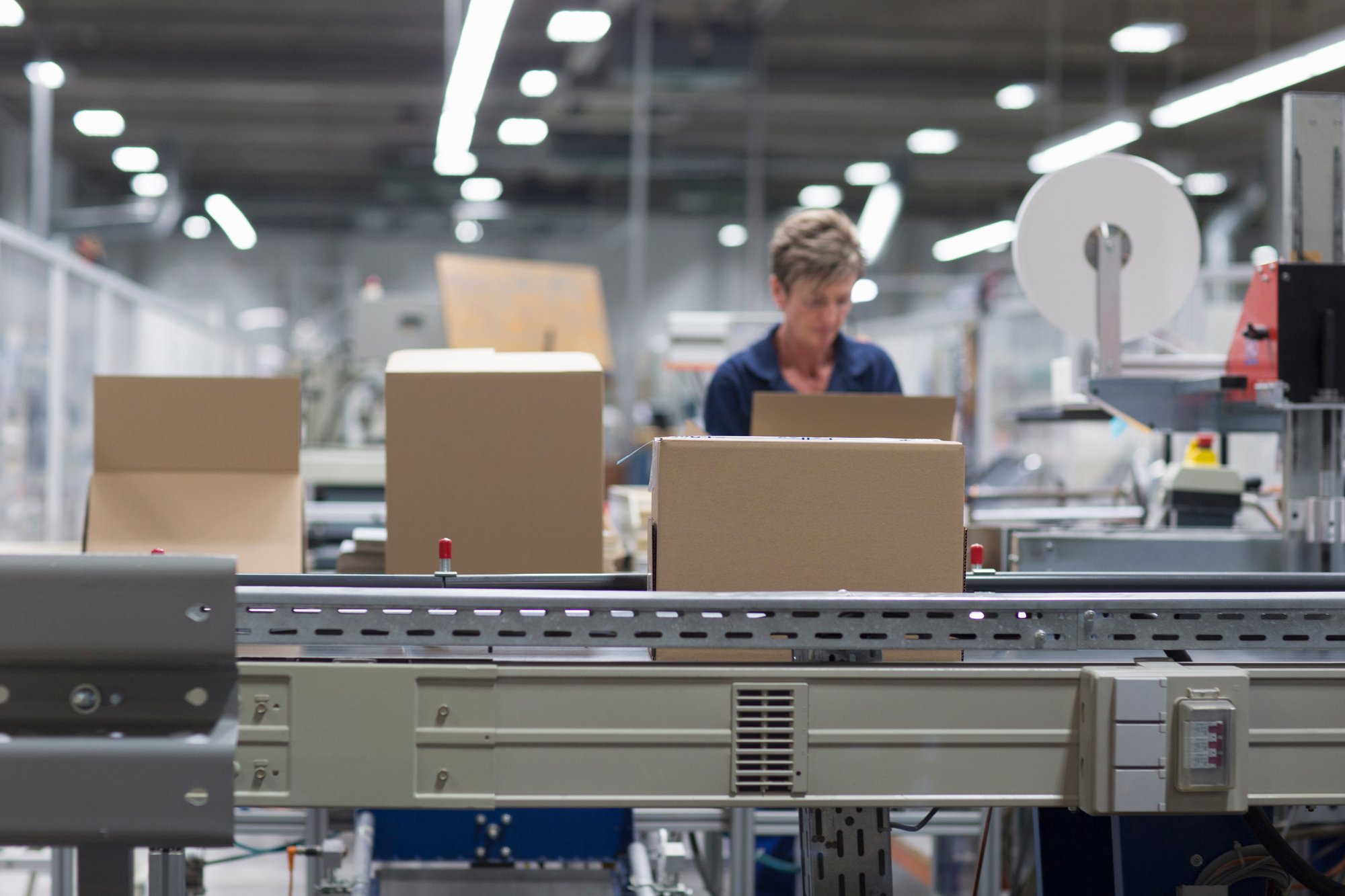 Operator working beside cardboard boxes on a packaging line