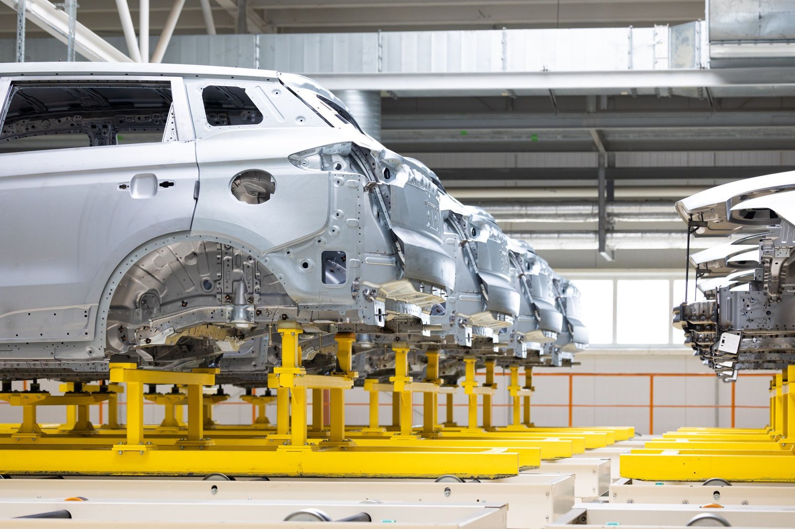 Unpainted car bodies on yellow jigs in a body shop