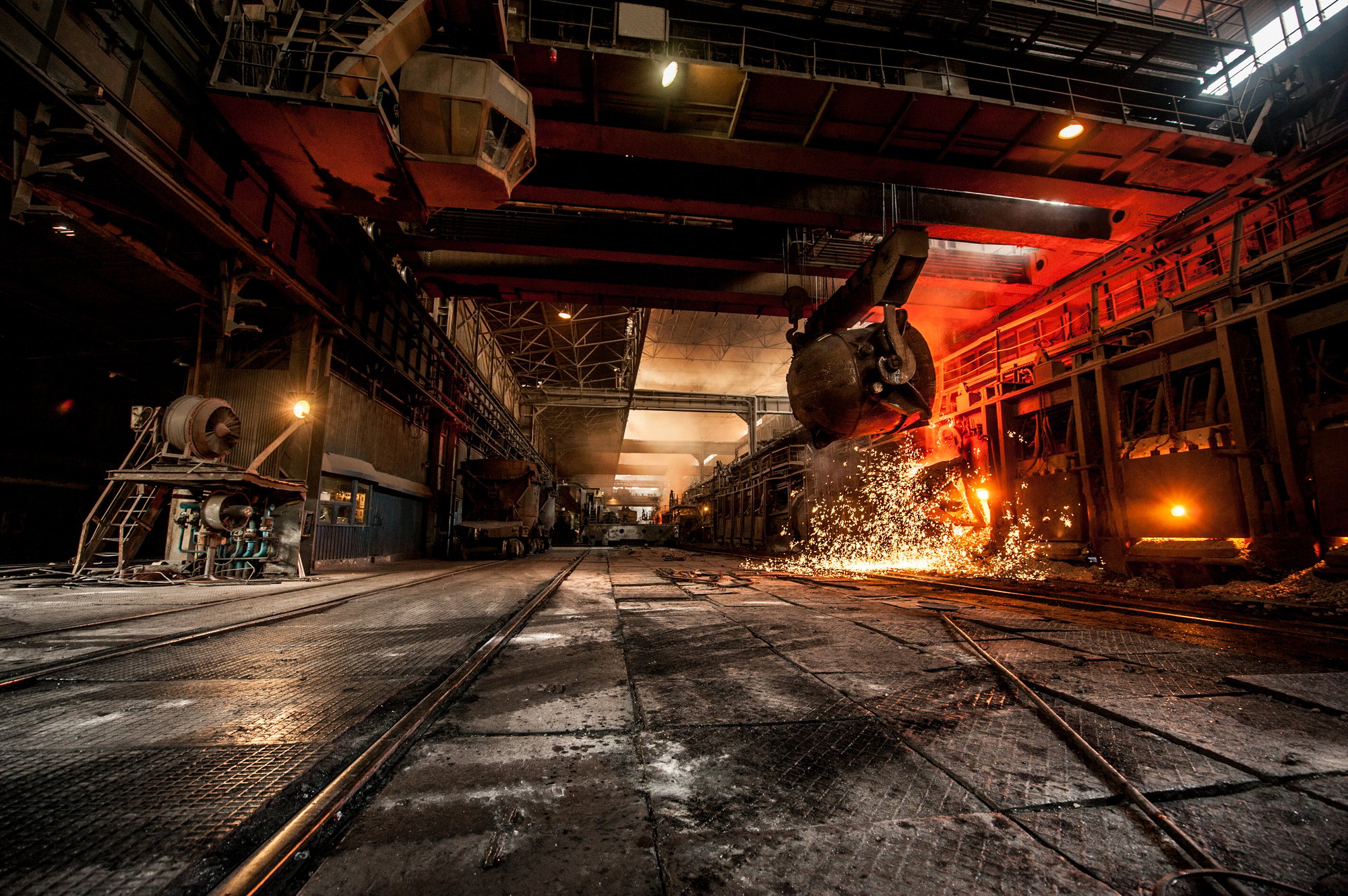 Steel mill casting hall with a ladle pouring under an overhead crane