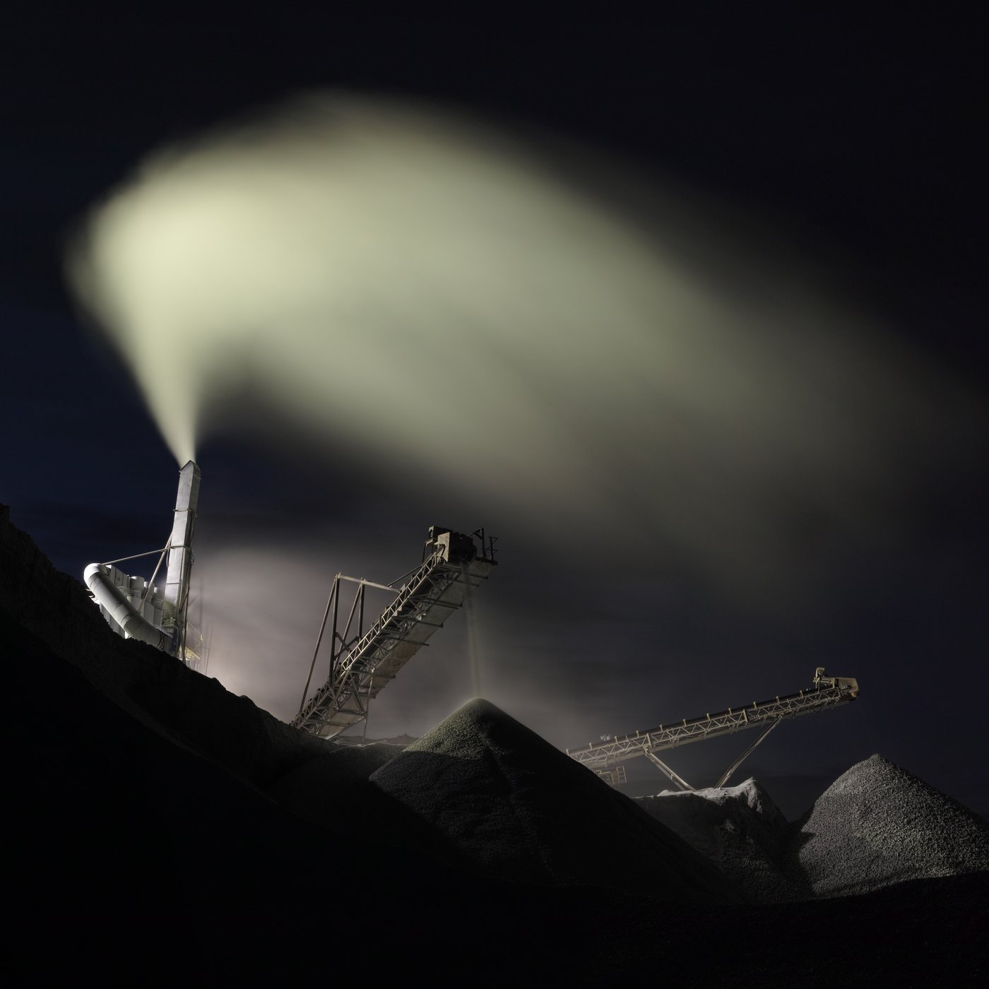 Processing equipment releasing a vapor plume at night