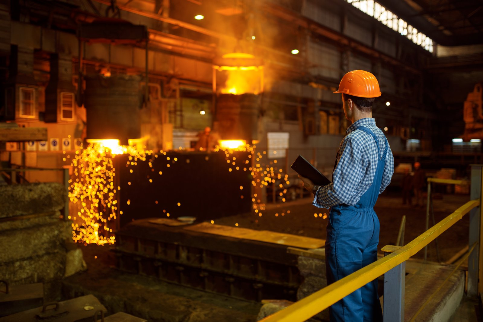 Engineer in a hard hat watching a pour on the melt shop floor